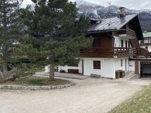 una casa con un albero di fronte di Casa Ca dei Pini a Cortina dʼAmpezzo
