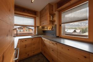 una cocina con armarios de madera y una gran ventana en Casa Ca dei Pini en Cortina dʼAmpezzo
