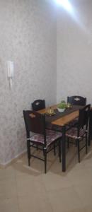 a dining room table with four chairs and a phone at Bel appartement à 5min de la plage in Tangier