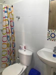 a white bathroom with a toilet and a sink at Cabaña la Arenosa in Coveñas