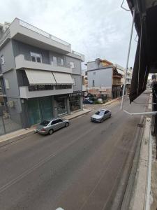 two cars driving down a city street with buildings at Appartment near centre, bus and train stations in Pyrgos
