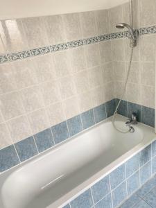 een badkamer met een bad en blauwe tegels bij Hotel des Sports in Deauville