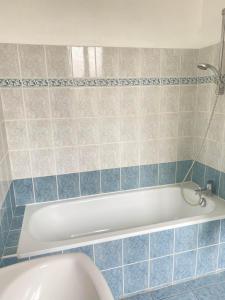 een badkamer met een wit bad en blauwe tegels bij Hotel des Sports in Deauville