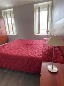 een slaapkamer met een rood bed en een lamp op een tafel bij Hotel des Sports in Deauville