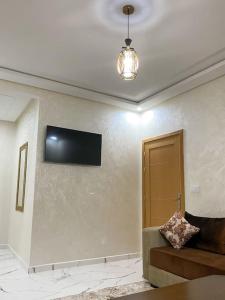 ein Wohnzimmer mit einem Sofa und einem TV an der Wand in der Unterkunft Appartement Familiale Al-Hoceima , Chic & cosy in Al Hoceïma