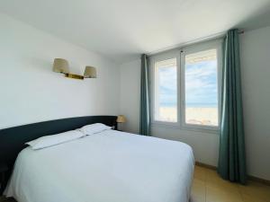 a bedroom with a white bed and a large window at Les Alizes in Palavas-les-Flots