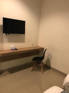 einen Schreibtisch mit einem TV und einem Stuhl in einem Zimmer in der Unterkunft The Holiday Guest House in Tanjungpandan
