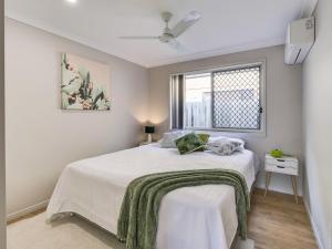 a bedroom with a bed with a green blanket on it at Breeze in Toogoom in Toogoom