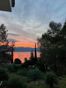 una puesta de sol sobre el agua con una torre en la distancia en Helen's appartments en Galaxidi