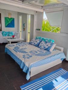 a bedroom with a bed with blue and white pillows at Poppies Beach Bach in Matavera