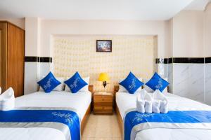 Duas camas num quarto com almofadas azuis e brancas em KHÁCH SẠN HỒNG PHÁT em Ho Chi Minh