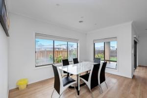 a dining room with a table and chairs and windows at Spacious 3BR Family Home With Bright Style Living in Point Cook