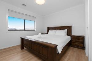 - une chambre avec un grand lit et une fenêtre dans l'établissement Spacious 3BR Family Home With Bright Style Living, à Point Cook
