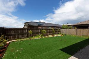 une cour avec une clôture et une pelouse verte dans l'établissement Spacious 3BR Family Home With Bright Style Living, à Point Cook