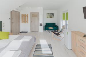 ein Wohnzimmer mit einem Bett und einem grünen Sofa in der Unterkunft Żabi Staw in Supraśl