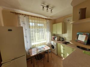 cocina con nevera, mesa y ventana en Kandavas 2 en Daugavpils