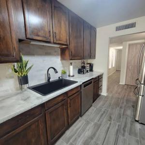 a kitchen with wooden cabinets and a sink at Desert Oasis With Hot Tub! in Las Cruces