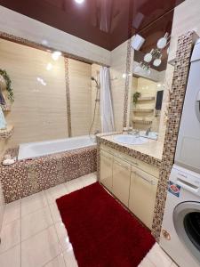 La salle de bains est pourvue d'une baignoire, d'un lavabo et d'un tapis rouge. dans l'établissement Relax. Просторі та затишні апартаменти, à Ternopil
