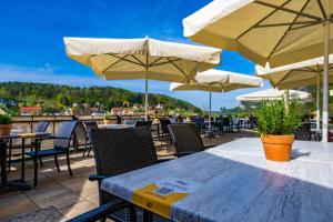 einen Tisch und Stühle mit Sonnenschirmen auf einer Terrasse in der Unterkunft STEIGER Hotel Rathener Hof in Kurort Rathen