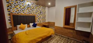 a bedroom with a bed with a yellow blanket at Hogwartz Hostel in Kasol