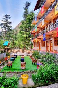 une cour avec des tables et des bancs dans un bâtiment dans l'établissement Hogwartz Hostel, à Kasol