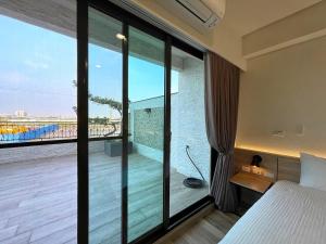 Schlafzimmer mit einem großen Fenster mit Blick auf einen Balkon in der Unterkunft 戀戀館民宿 in Tainan