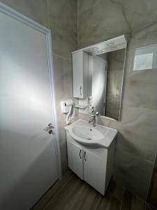 a white bathroom with a sink and a mirror at VILA AARON in Durrës