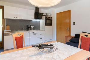 a kitchen with white cabinets and a table with chairs at Ferienwohnung Michael Novablick in Gaschurn