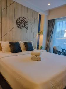 ein großes weißes Bett mit zwei Handtüchern darauf in der Unterkunft Carapace Residents Huahin-Khaotao in Khao Tao