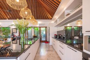 a large kitchen with black counter tops and glass chandeliers at Villa Mimpi Nyata in Canggu