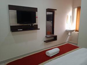 um quarto com uma cama, uma televisão e um tapete vermelho em SRI BHAVYARESIDENCY em Bhadrachalam