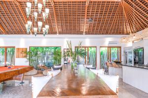 Un comedor con una gran mesa y sillas de madera. en Villa Mimpi Nyata, en Canggu