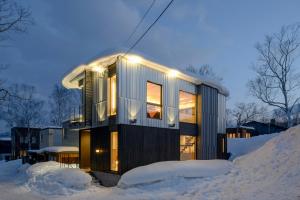 una casa en la nieve con luces encendidas en Hachiko by H2 Life en Kutchan