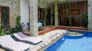 two lounge chairs sitting next to a swimming pool at The Lavana Jasmine Villa in Senggigi