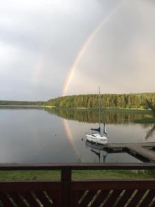 a rainbow over a dock with a sail boat on a lake at Kołatek Mazury Apartament z widokiem in Olsztynek