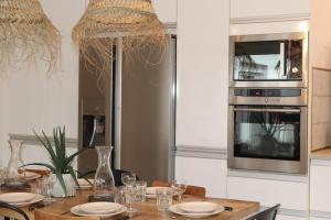 La Maison du Bonheur 195 m2 - Piscine - Jacuzzi - Proche Plage في ايمارغوس: مطبخ مع طاولة مع لوحات وميكروويف