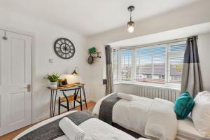 a bedroom with two beds and a clock on the wall at Stylish Maisonette near the heath with Free parking & Wi-Fi in Kent