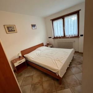 a small bedroom with a bed and a window at Trentino Apartments - Casa ai Fiori in Folgaria