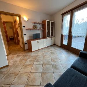- un salon avec un canapé et une grande fenêtre dans l'établissement Trentino Apartments - Casa ai Fiori, à Folgaria
