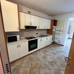 a kitchen with white cabinets and a tile floor at Trentino Apartments - Casa ai Fiori in Folgaria