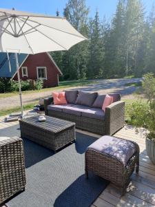 um pátio com um sofá, cadeiras e um guarda-sol em VillaTorppa em Jämsä