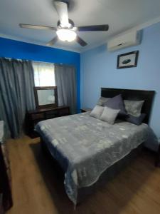 - une chambre bleue avec un lit et un ventilateur de plafond dans l'établissement 23 Wawiel Guesthouse, à Orkney