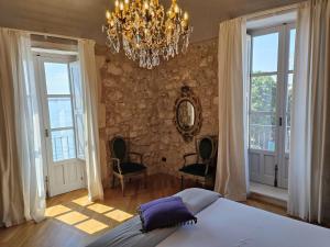 a bedroom with a bed and a chandelier and windows at Dimora Aretusa Luxury in Siracusa