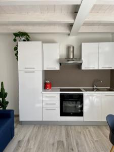 cocina con armarios blancos y fogones en Appartamenti Le Tre Rose, en Nago-Torbole