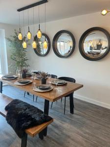 a dining room table with mirrors on the wall at Outstanding 4-Bedroom Town House By Valore Property Services in Milton Keynes