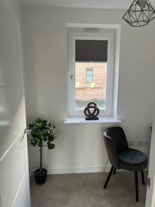 a room with a chair and a window at Outstanding 4-Bedroom Town House By Valore Property Services in Milton Keynes