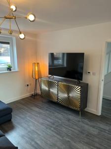 a living room with a large television and a lamp at Outstanding 4-Bedroom Town House By Valore Property Services in Milton Keynes