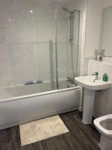 La salle de bains est pourvue d'une baignoire, d'un lavabo et de toilettes. dans l'établissement Outstanding 4-Bedroom Town House By Valore Property Services, à Milton Keynes