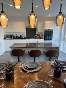 a kitchen with a wooden table with chairs and a counter at Outstanding 4-Bedroom Town House By Valore Property Services in Milton Keynes