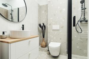 y baño con aseo, lavabo y espejo. en Manpro Apartments Toruń en Toruń